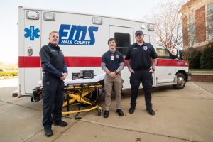 Three EMS personnel in front of ambulance