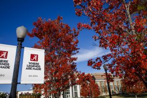 Trees with red leaves set against blue sky. Light poles with white banners that read "Where Legends Are Made"