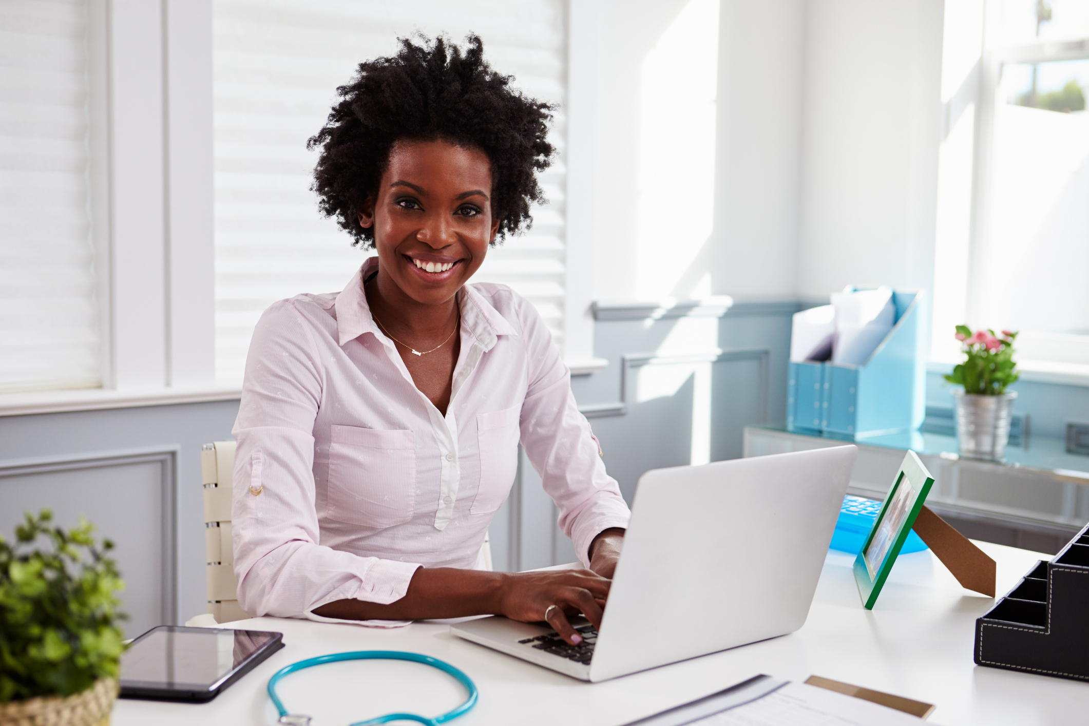 Black female doctor at work in an office, looking to camera