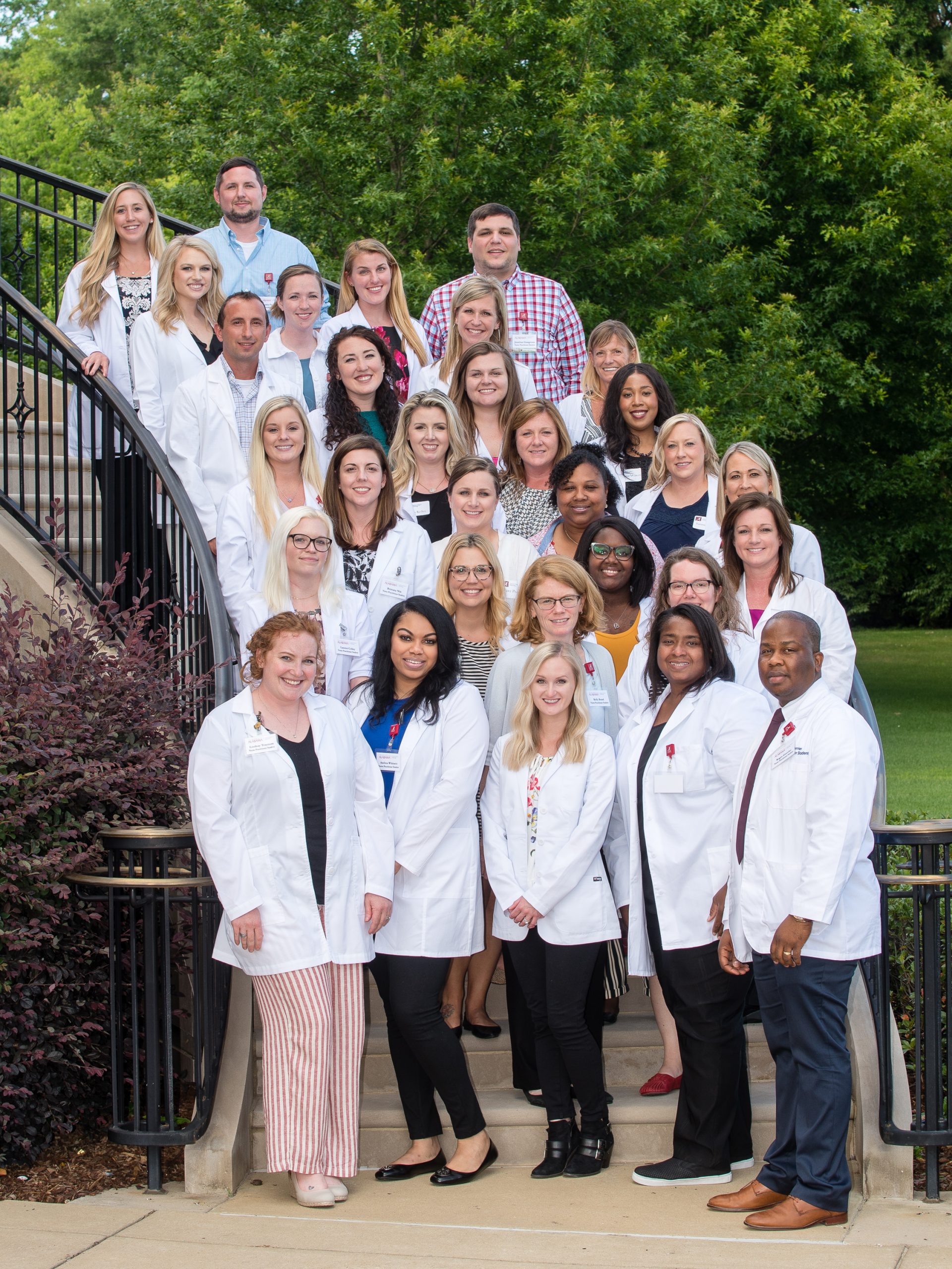 group of nurse practitioner students in white coats standing on the steps of the CCN building