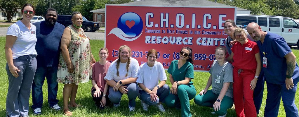 A group of CCN faculty, students and community partners in front of CHOICE Resource Center sign.